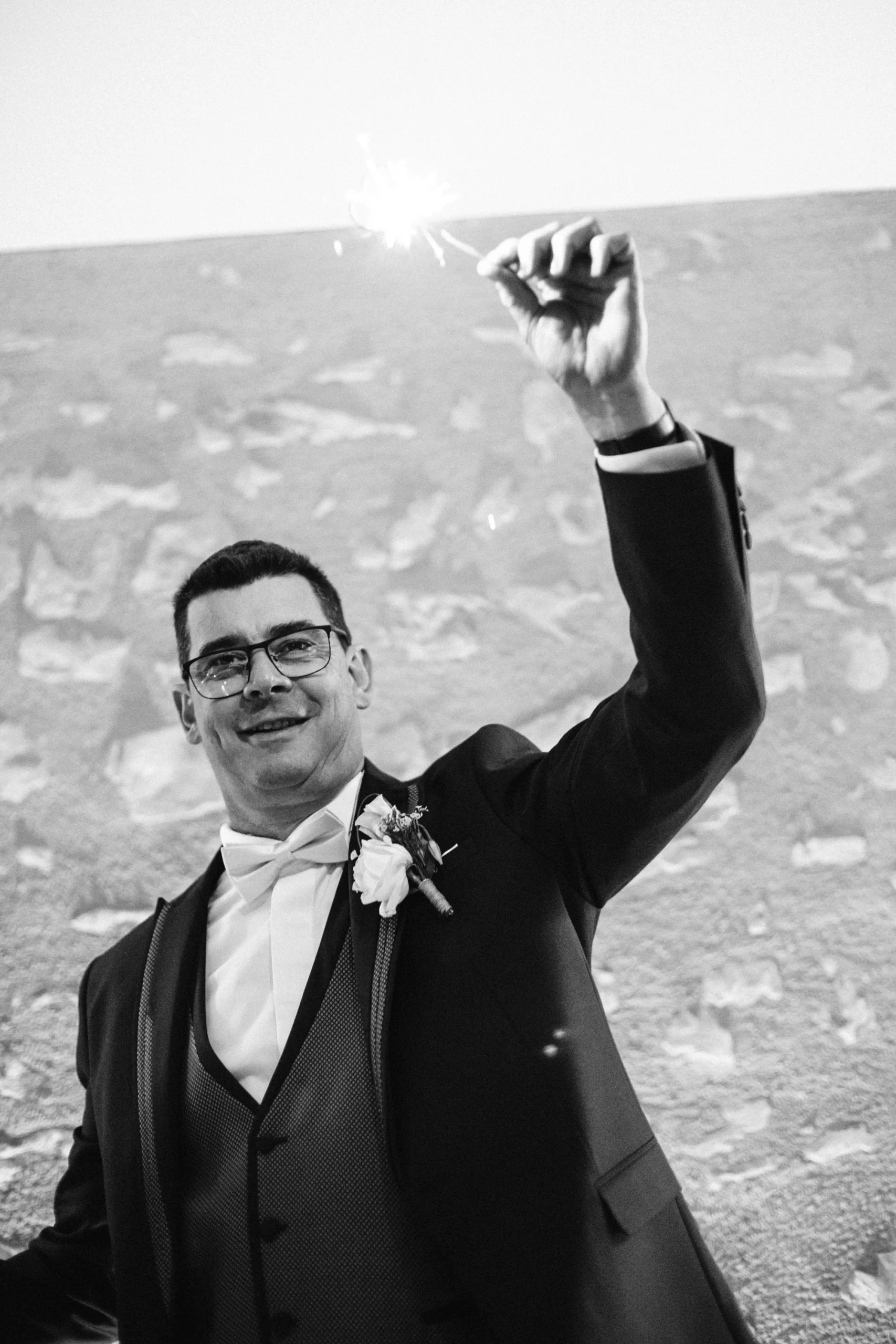 Marié levant le bras sous les confettis, photo de mariage en noir et blanc à Bourges