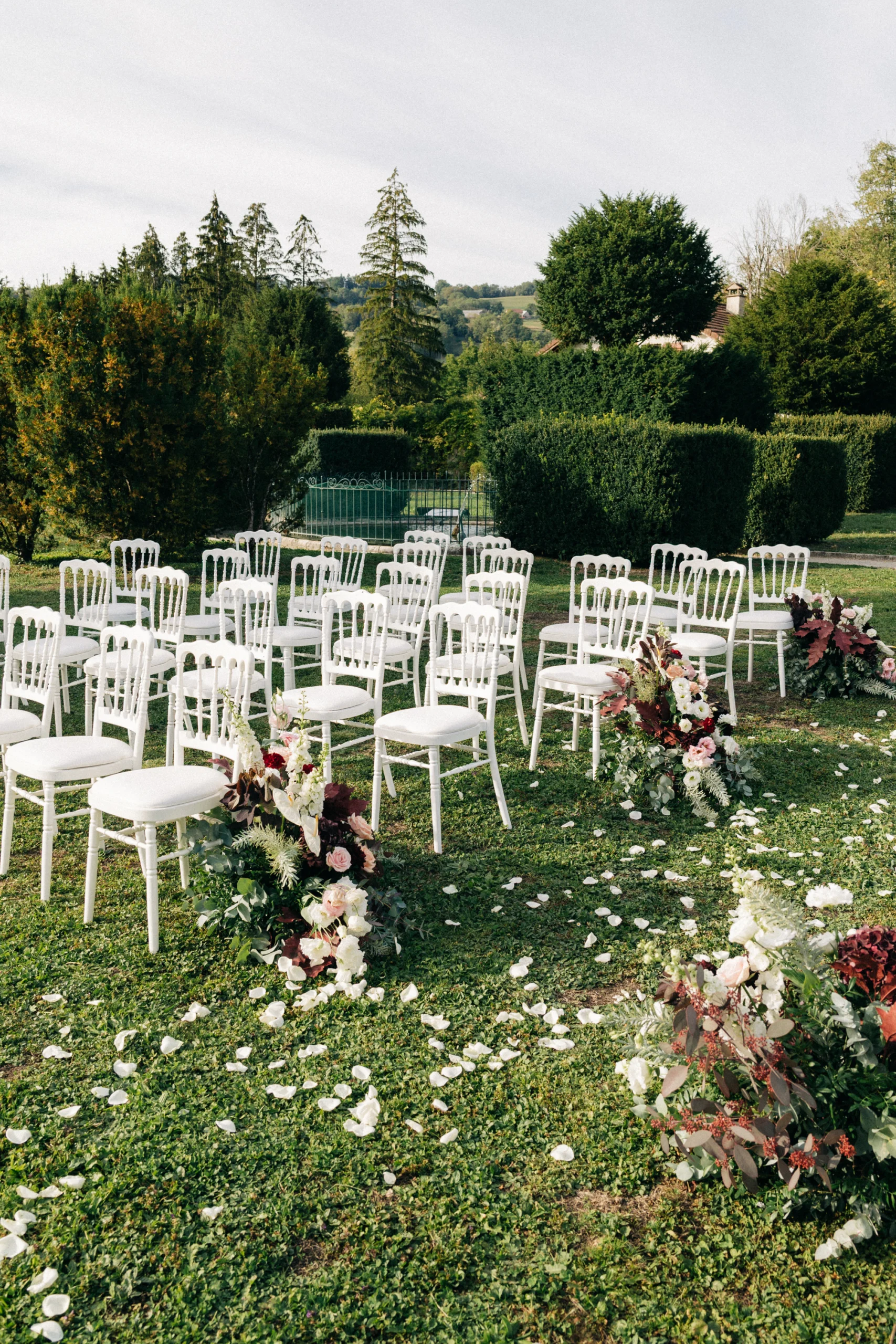 Chaises blanches et allée fleurie de la cérémonie laïque dans le parc du château