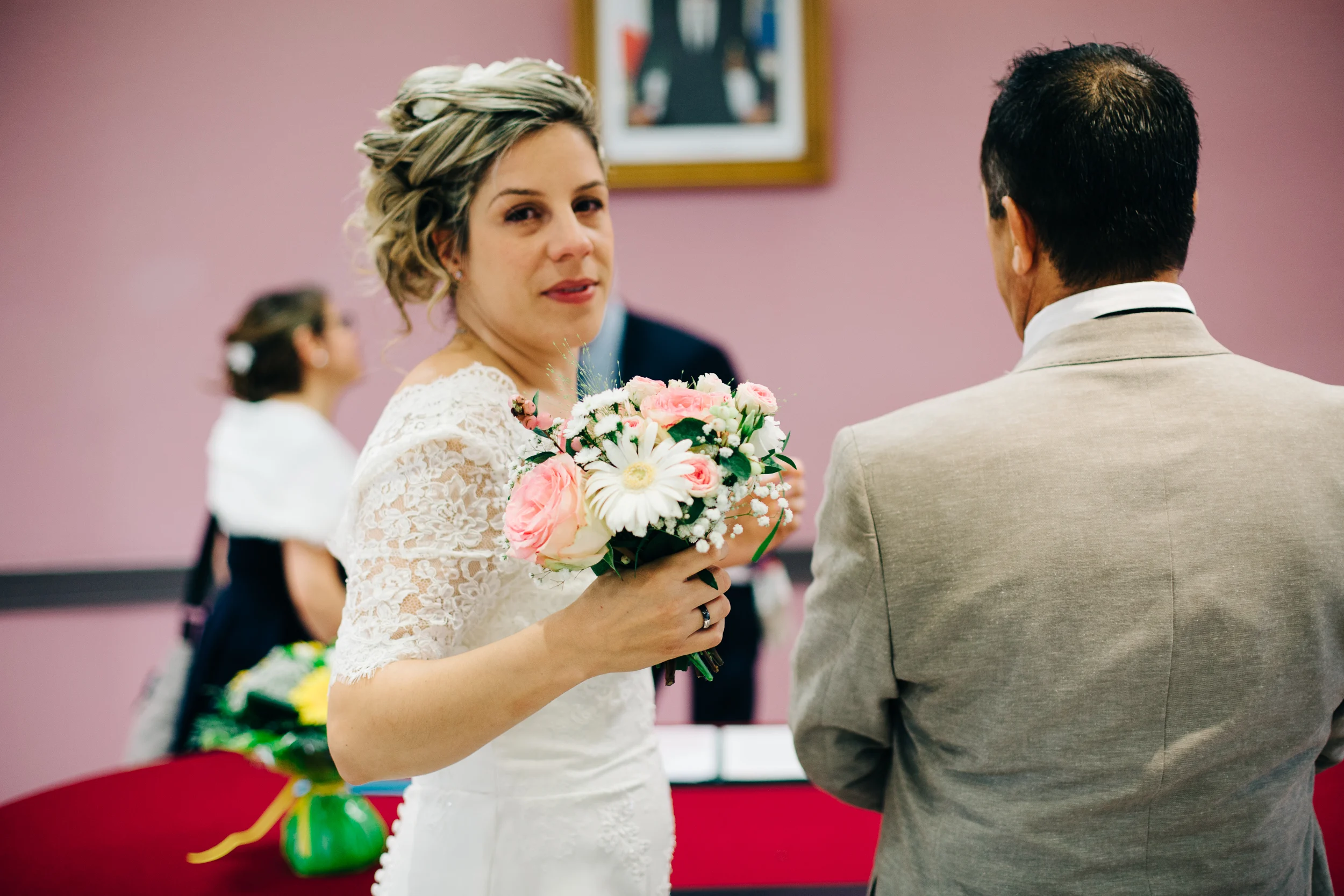Mariée en robe de dentelle tenant son bouquet de roses à la mairie