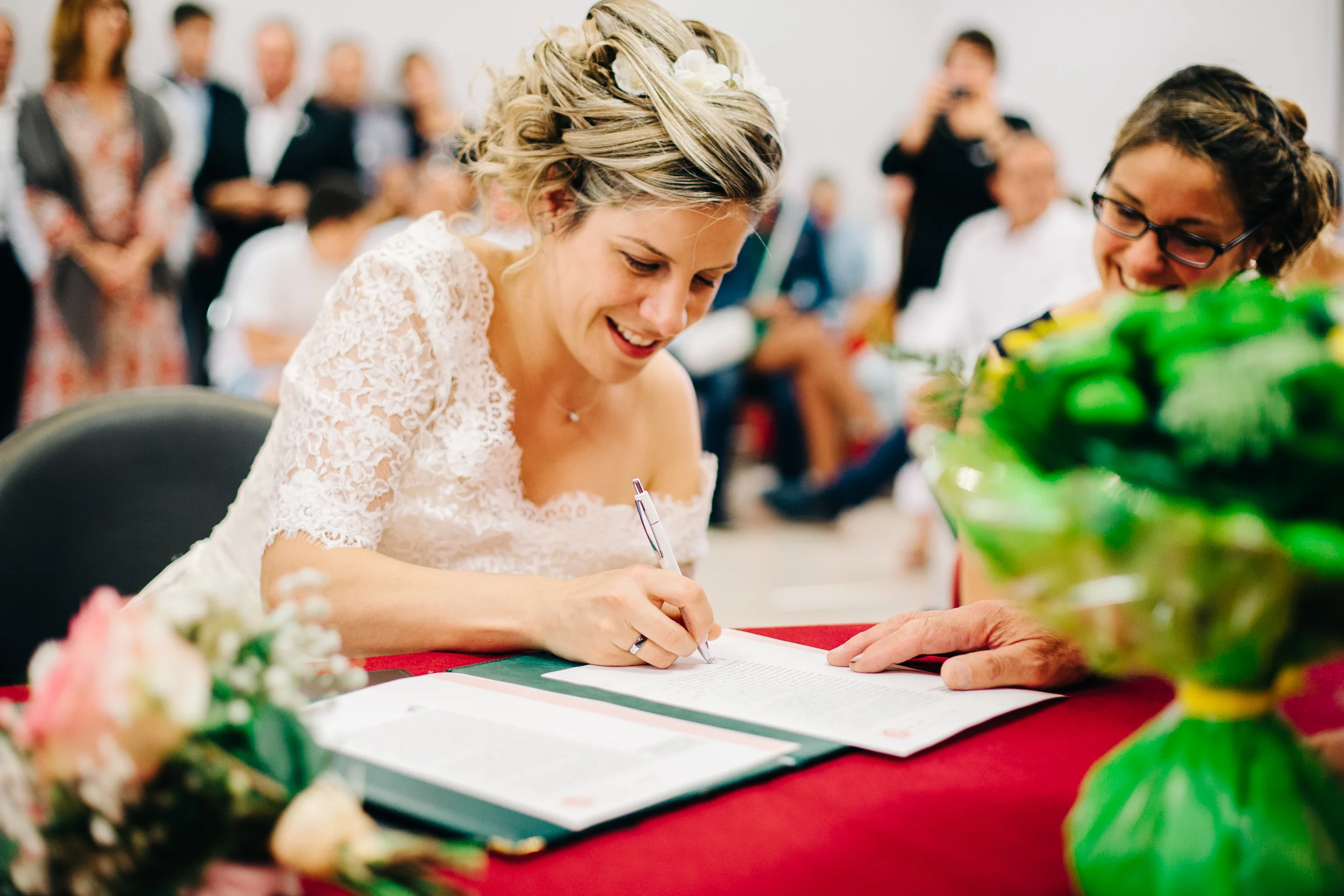 Mariée souriante signant le registre de mariage à la mairie