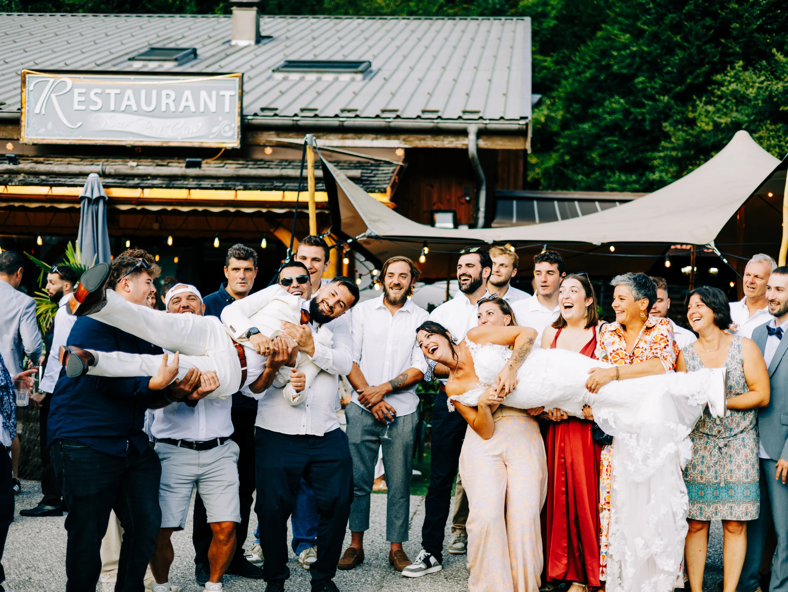 Invités portant les mariés à bout de bras devant le restaurant de la réception à La Clusaz
