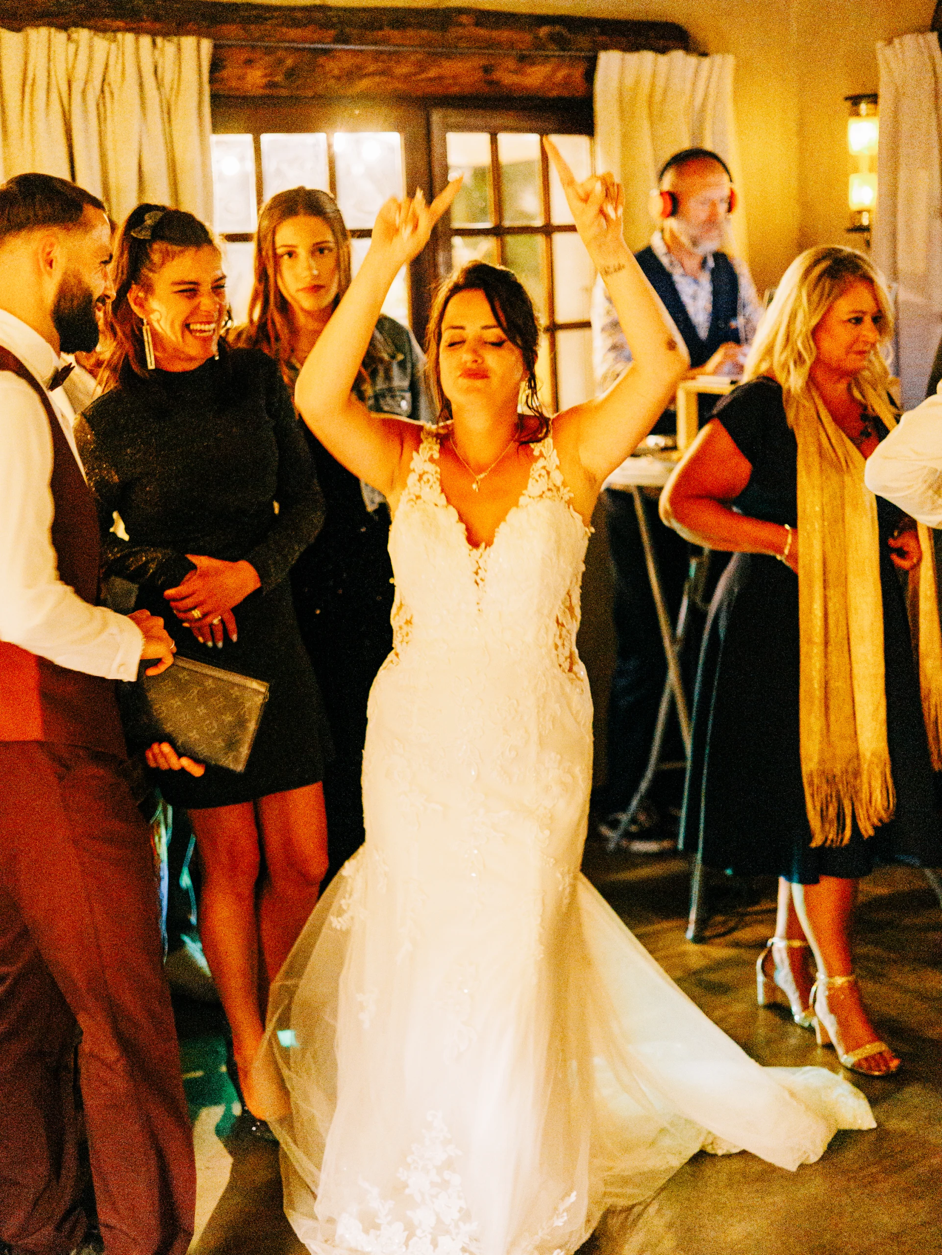 Mariée dansant les bras levés au milieu des invités pendant la soirée de mariage