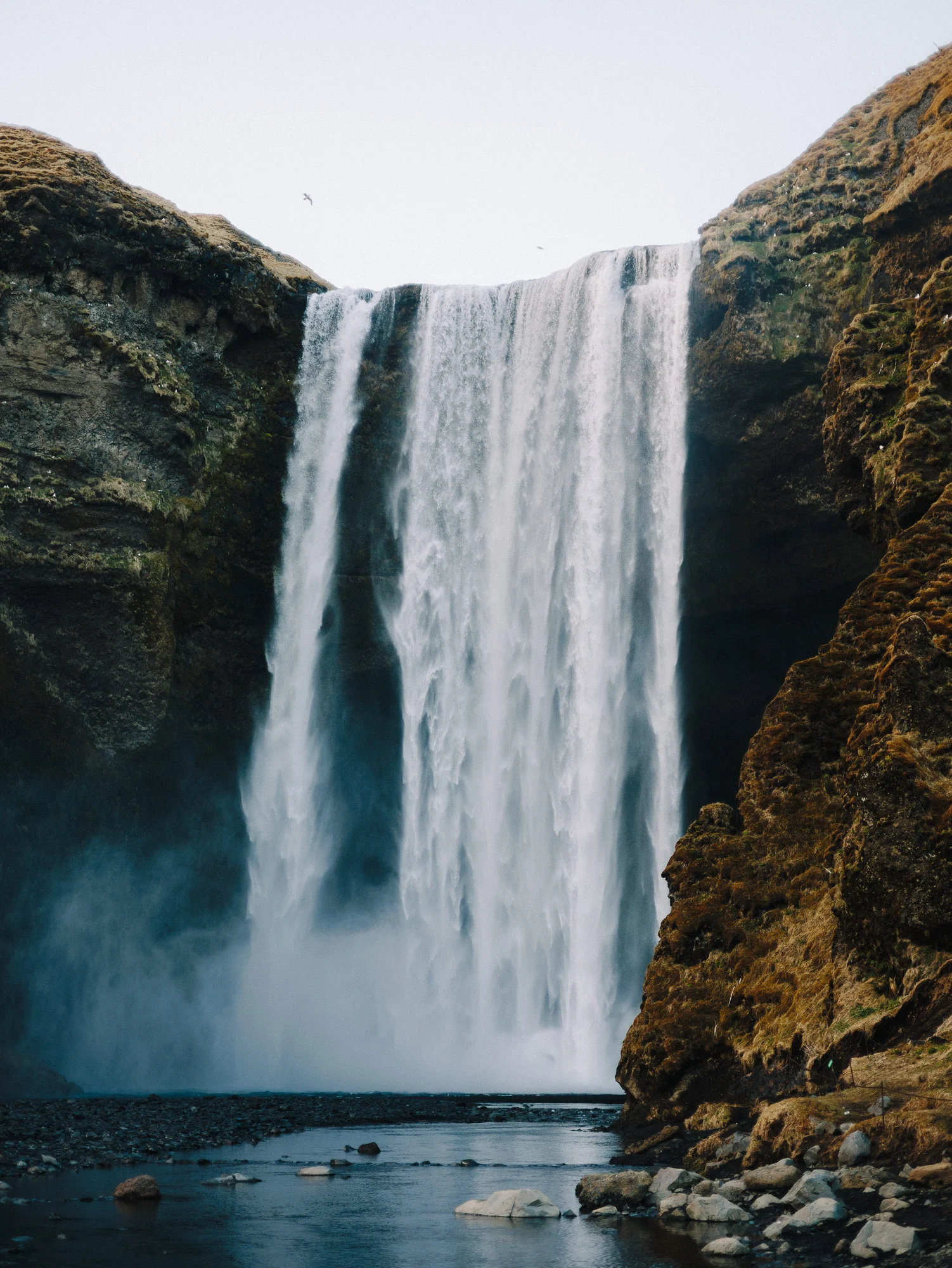 Cascade de Skógafoss tombant d'une falaise moussue, Islande