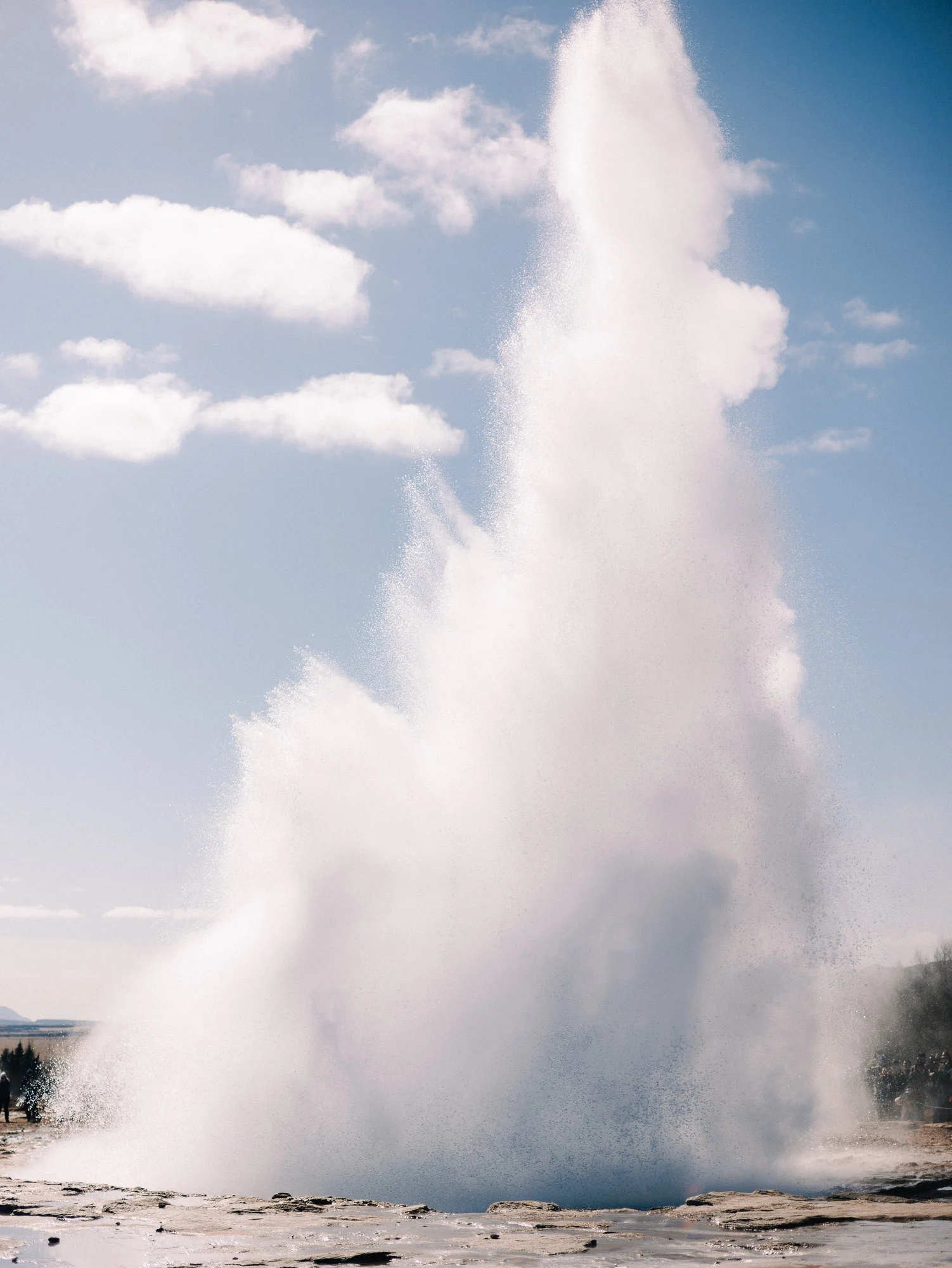 Jaillissement du geyser Strokkur sous un ciel bleu, Islande