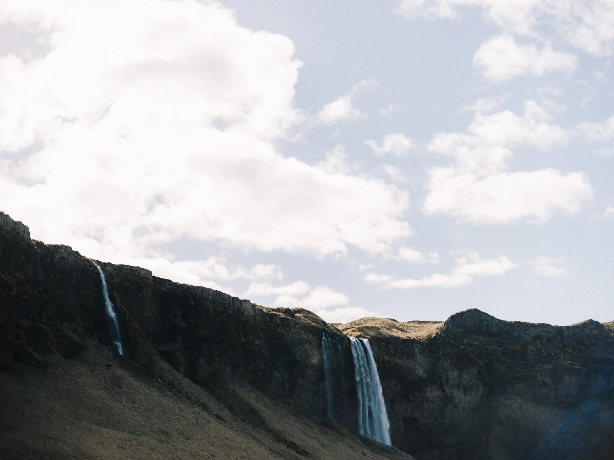 Falaise et fines cascades sous un ciel de nuages, sud de l'Islande