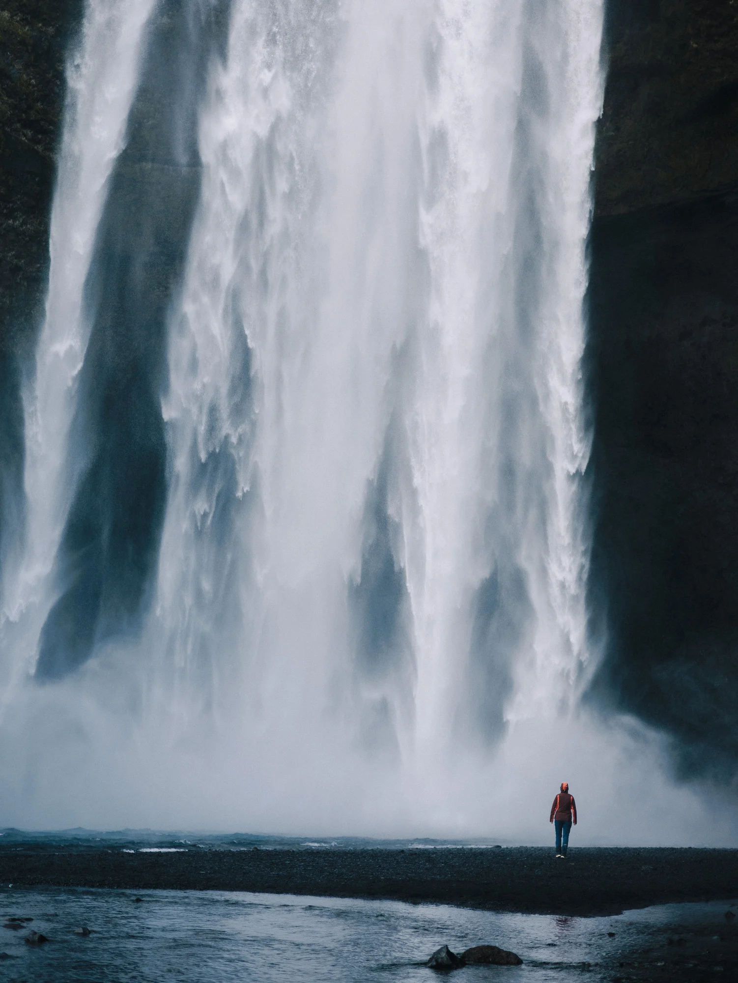 Randonneur minuscule au pied de la cascade de Skógafoss