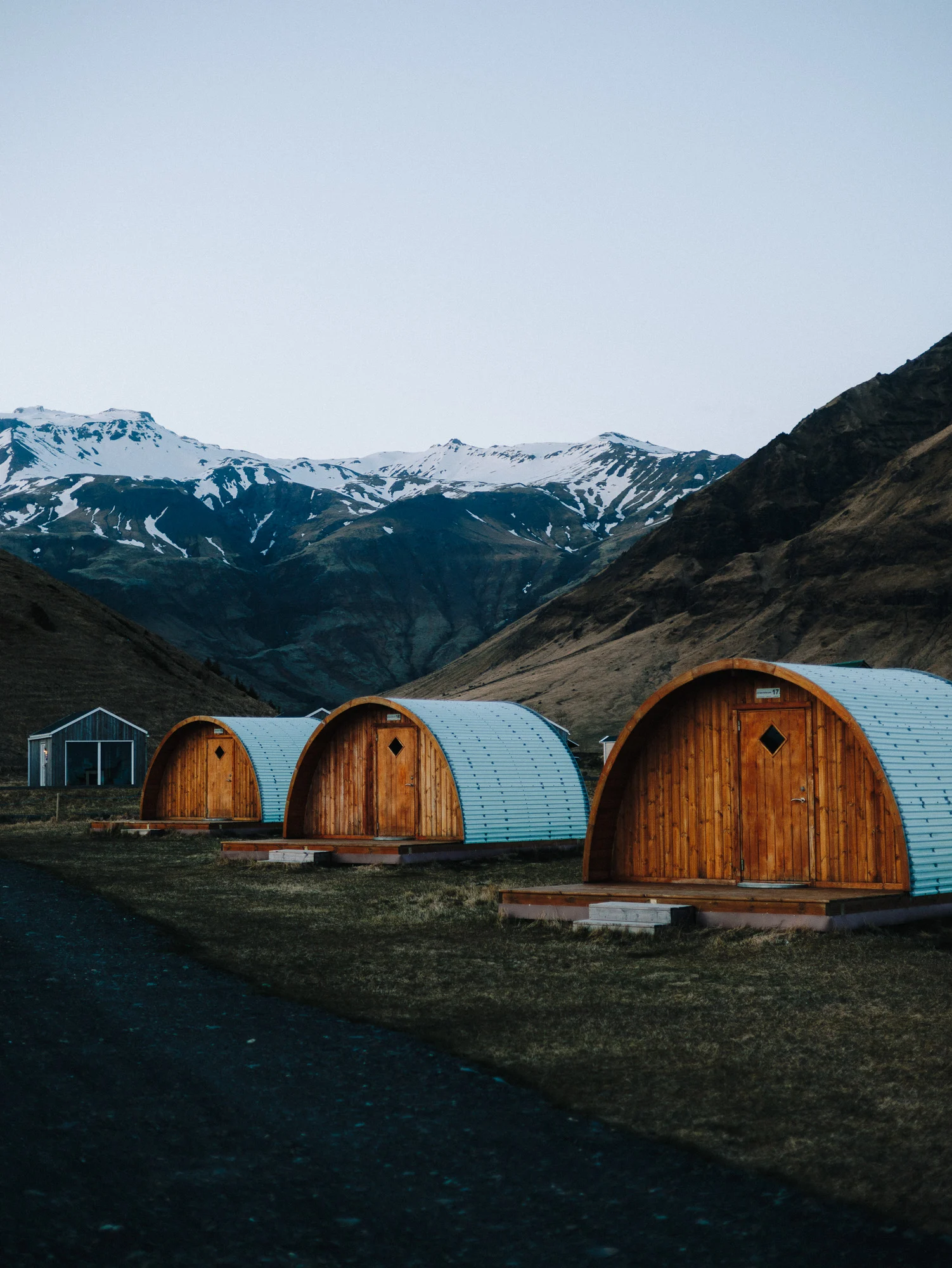 Cabanes en bois arrondies au pied des montagnes enneigées, Islande