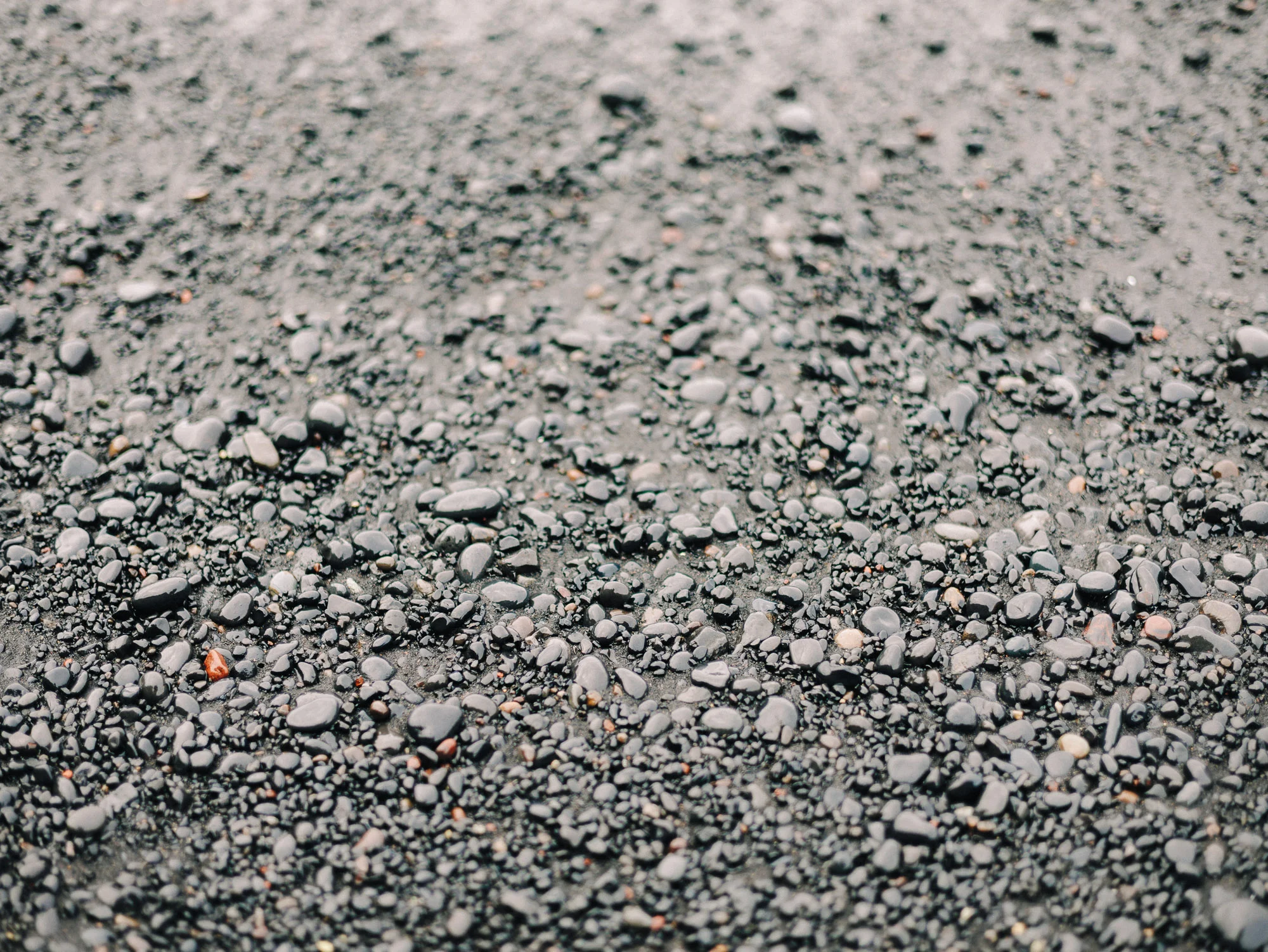 Gros plan sur le sable volcanique noir d'une plage islandaise