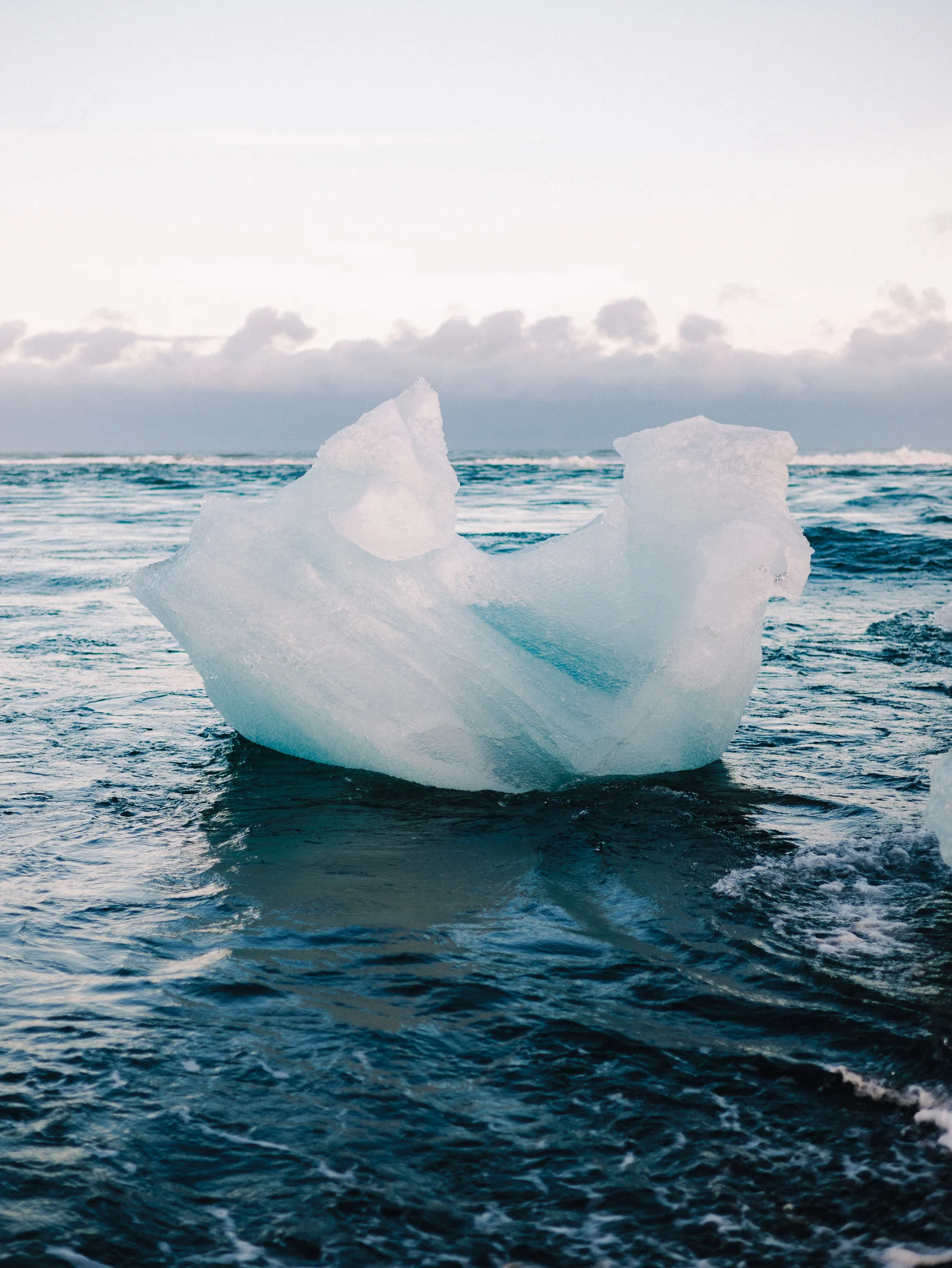 Bloc de glace translucide échoué dans les vagues de la Diamond Beach