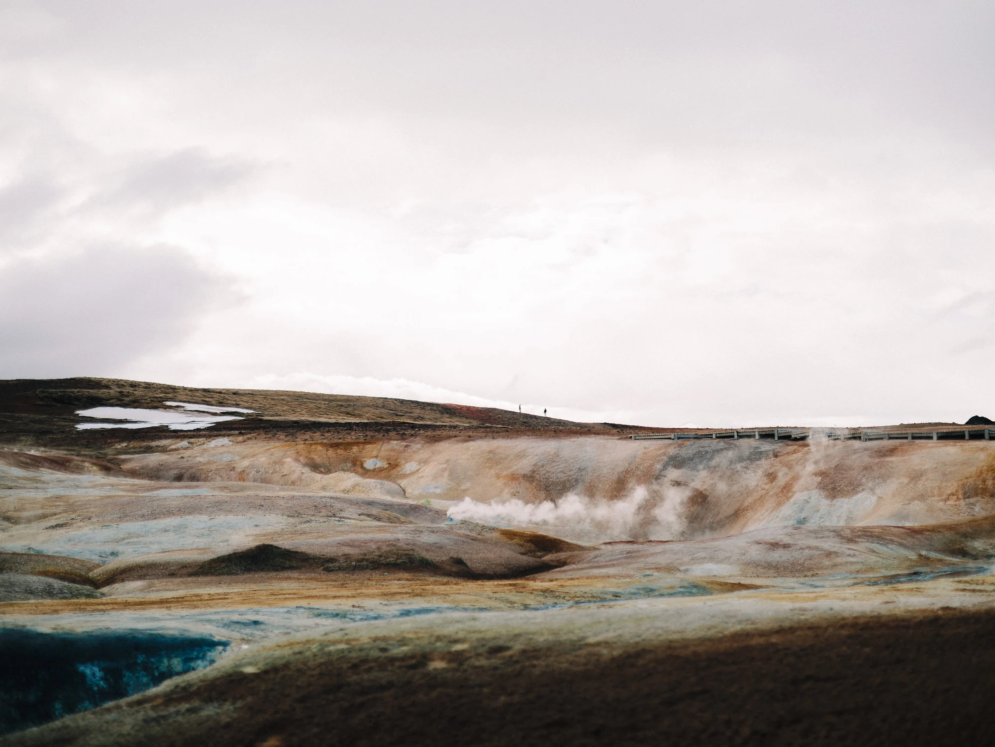 Champ géothermique ocre et fumant sous un ciel gris, nord de l'Islande