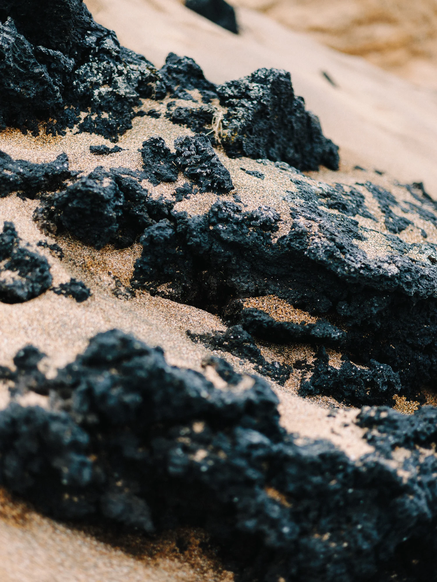 Roches de lave noire dans le sable clair, détail
