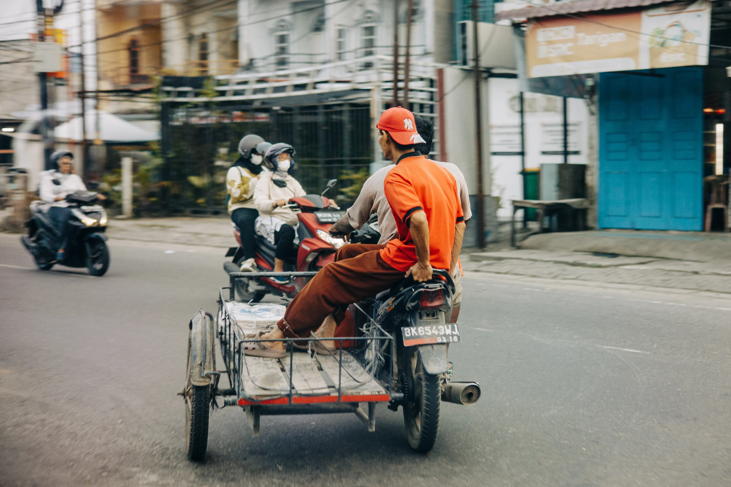 Becak, side-car traditionnel, et motos dans une rue de Sumatra