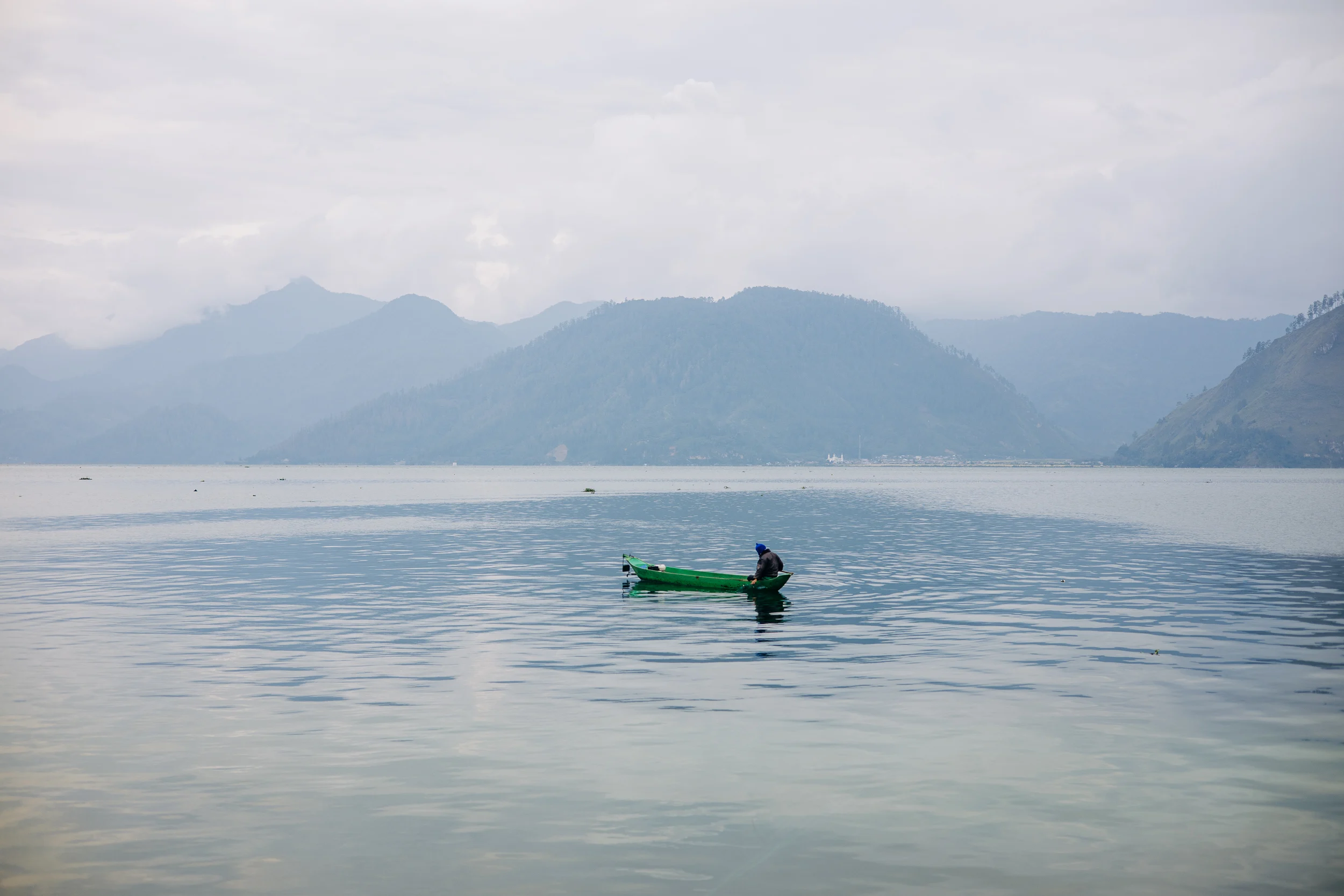 Pêcheur en barque sur un lac des hauts plateaux de Sumatra