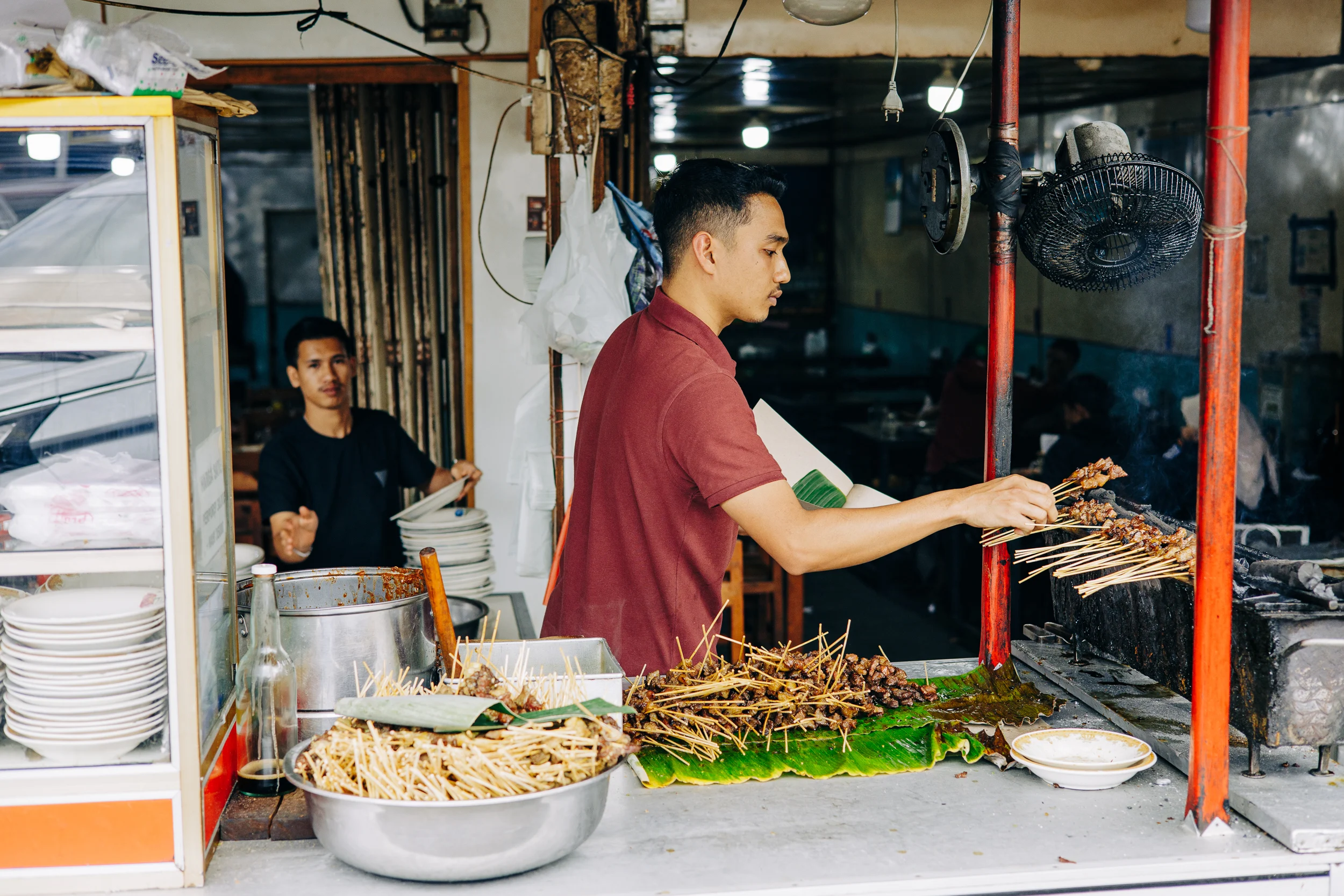 Cuisinier préparant des brochettes dans un restaurant de rue indonésien