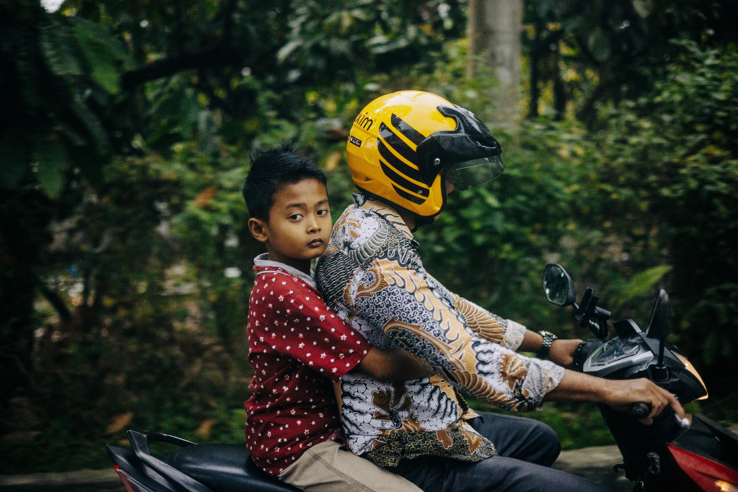 Enfant et adulte casqué sur un scooter, scène de rue à Sumatra