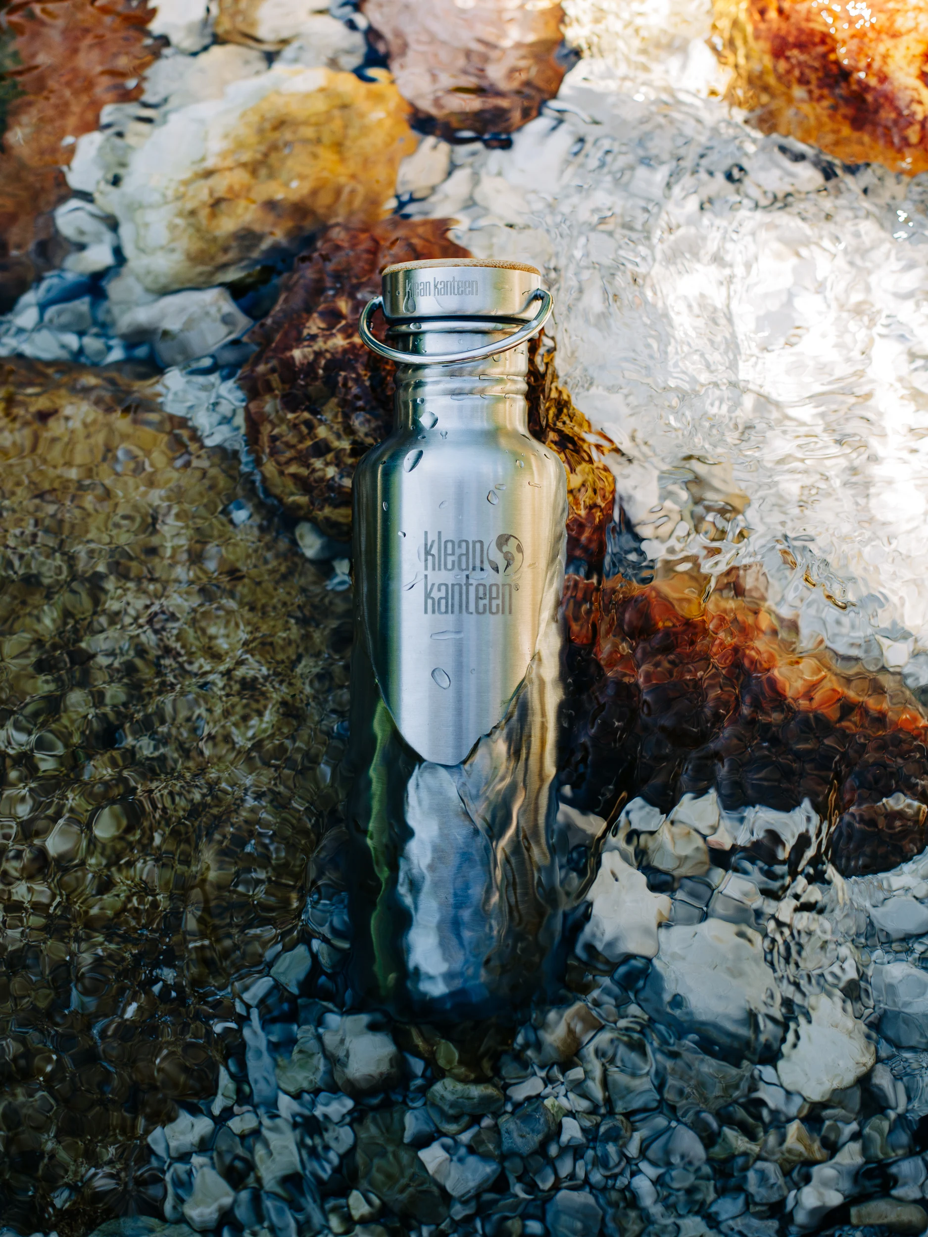 Gourde en inox Klean Kanteen posée dans l'eau claire d'une rivière