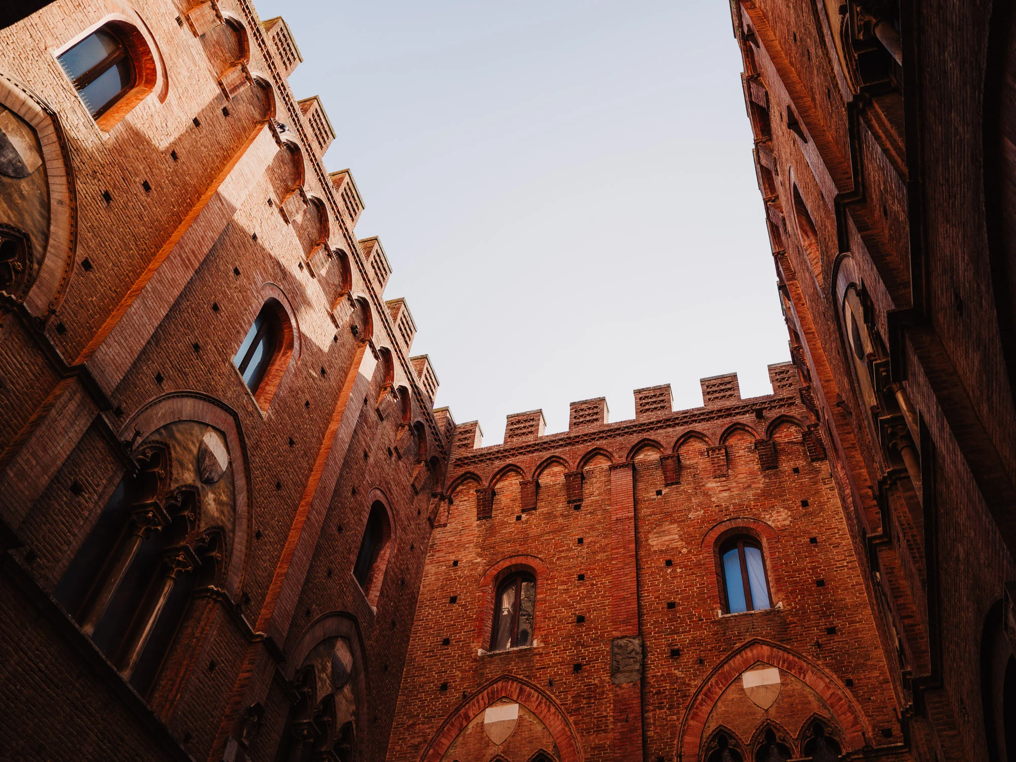 Palais médiéval en briques aux créneaux vu en contre-plongée, Toscane