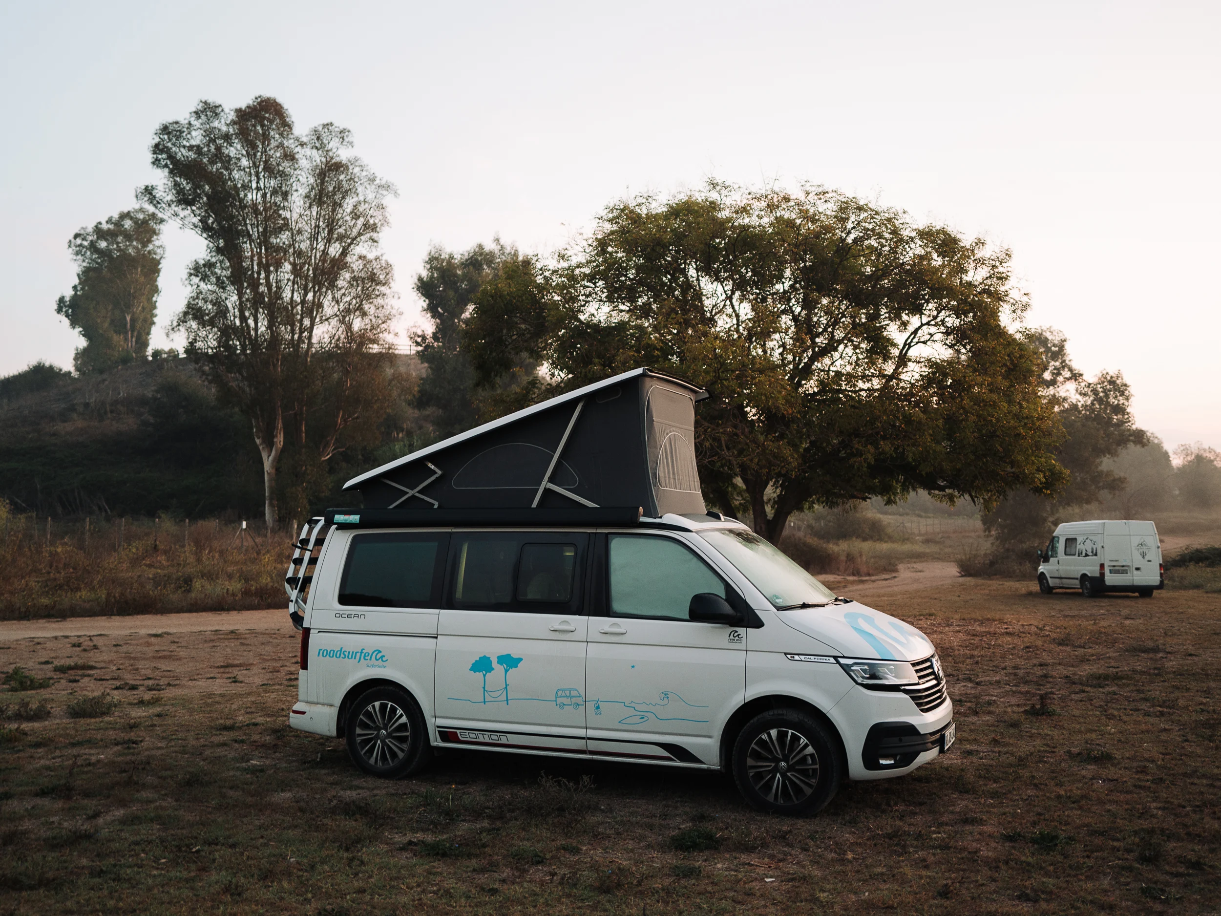 Van aménagé garé sous les arbres au lever du jour, road trip en Italie