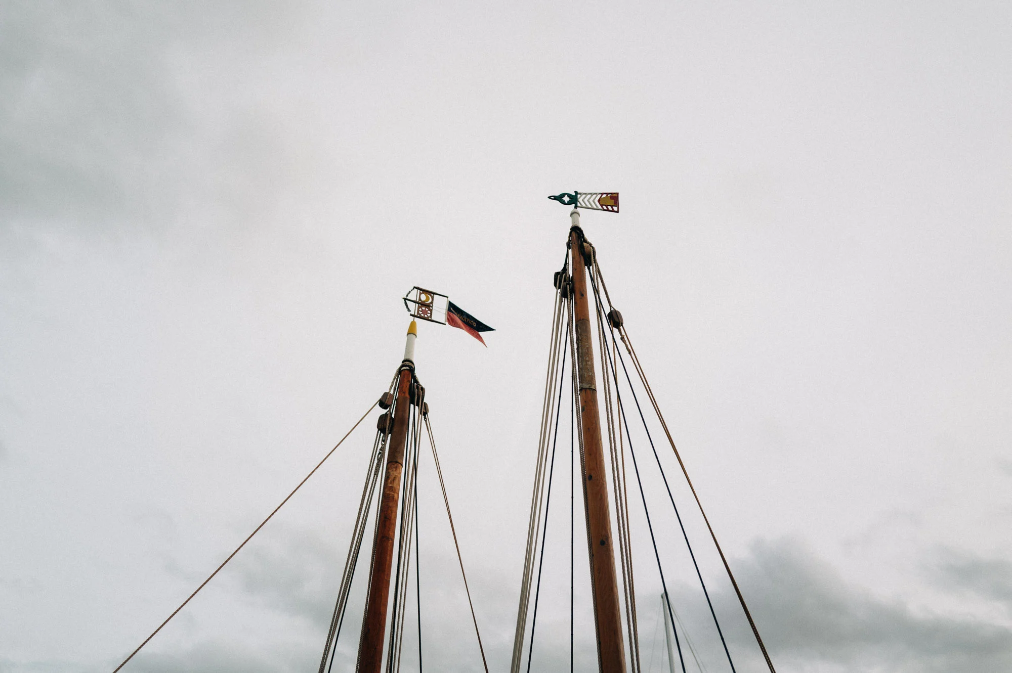 Mâts d'un voilier et drapeaux sous un ciel gris