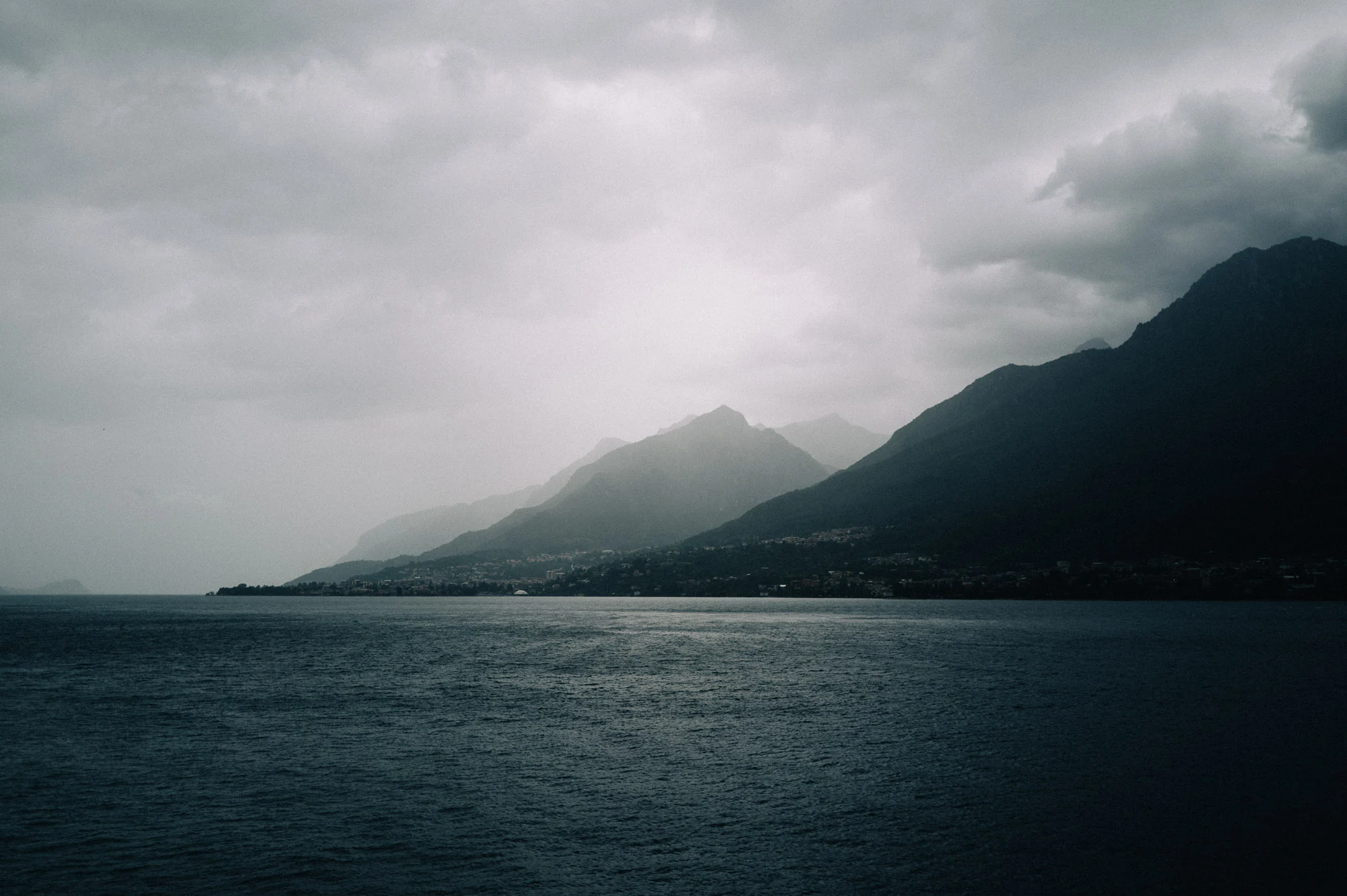 Lac de Côme sous un ciel d'orage, montagnes dans la brume
