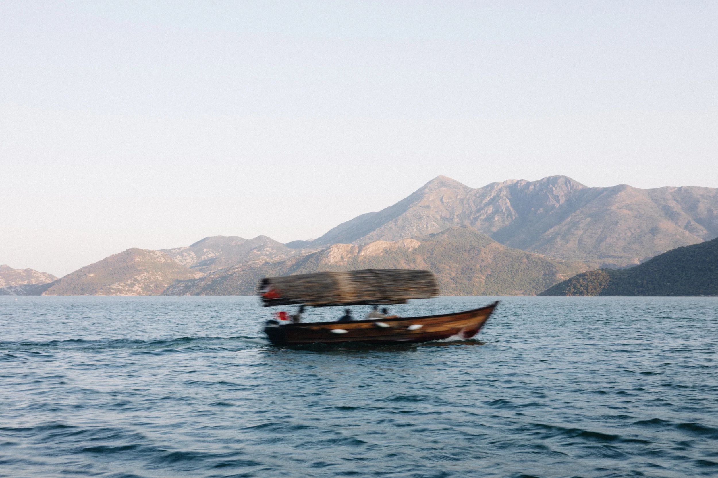 Bateau en bois traversant un lac entouré de montagnes