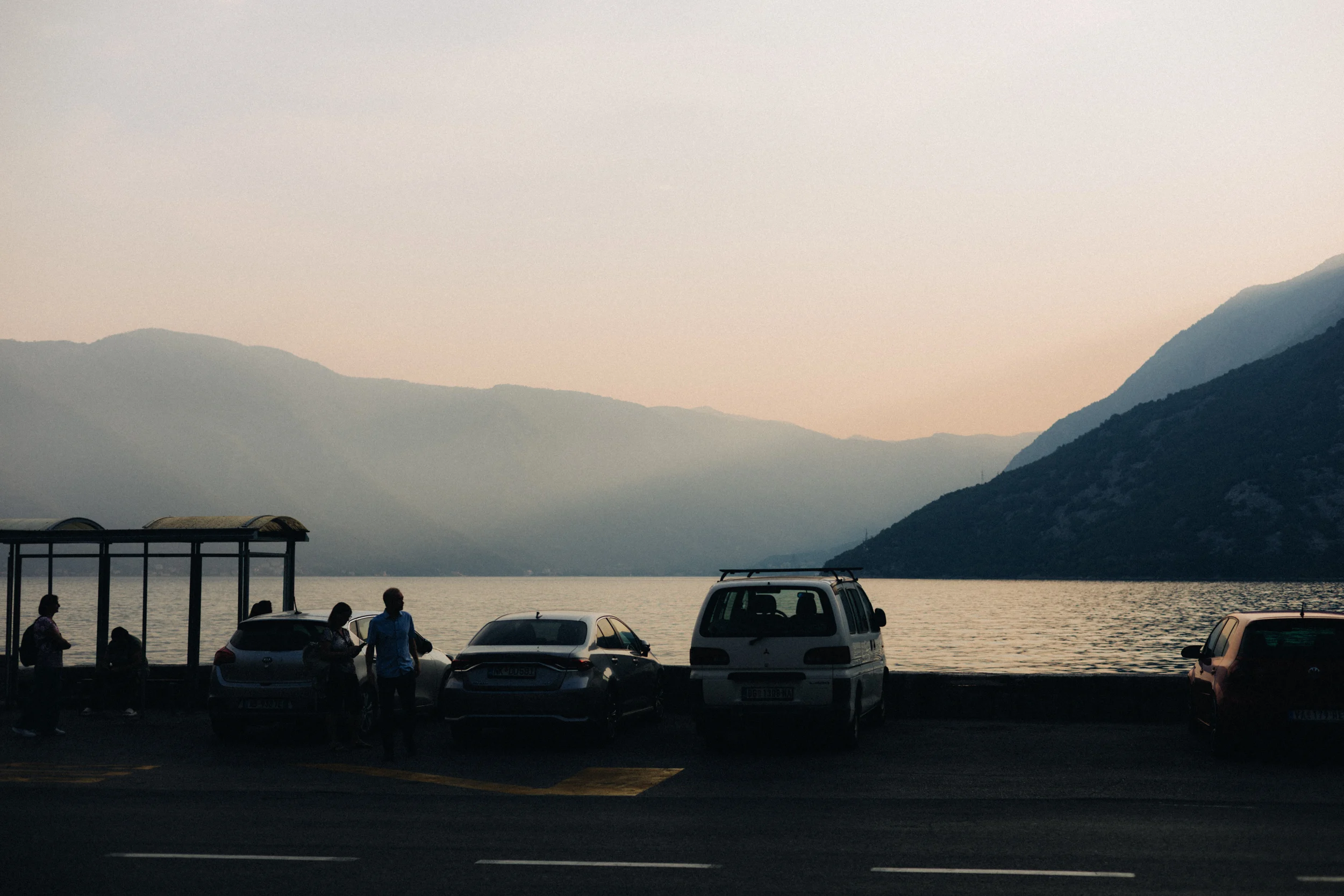 Baie de Kotor au coucher du soleil, voitures garées le long de la route côtière
