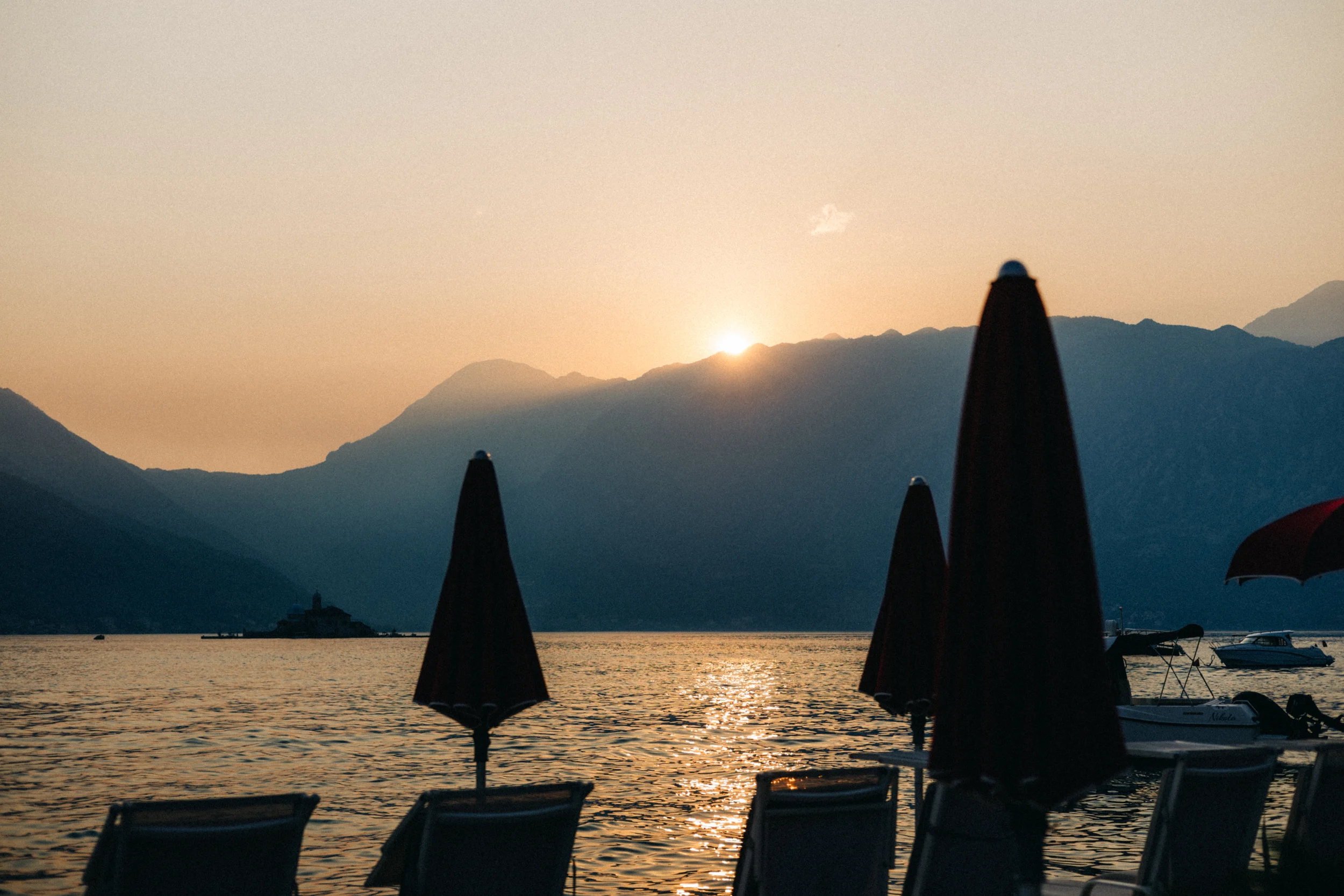 Coucher de soleil sur la baie de Kotor, parasols fermés au bord de l'eau