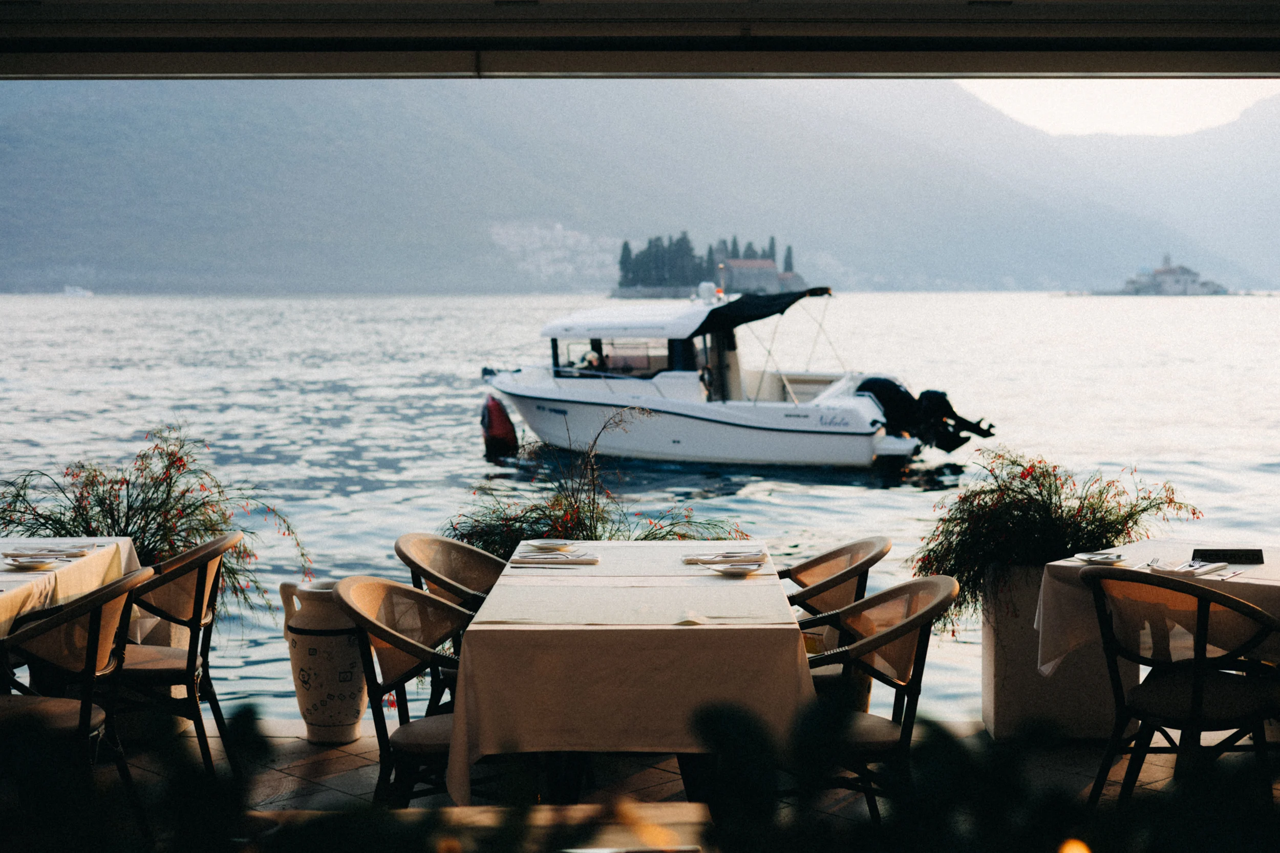 Bateau à moteur devant un îlot de la baie de Kotor, vu depuis une terrasse de Perast