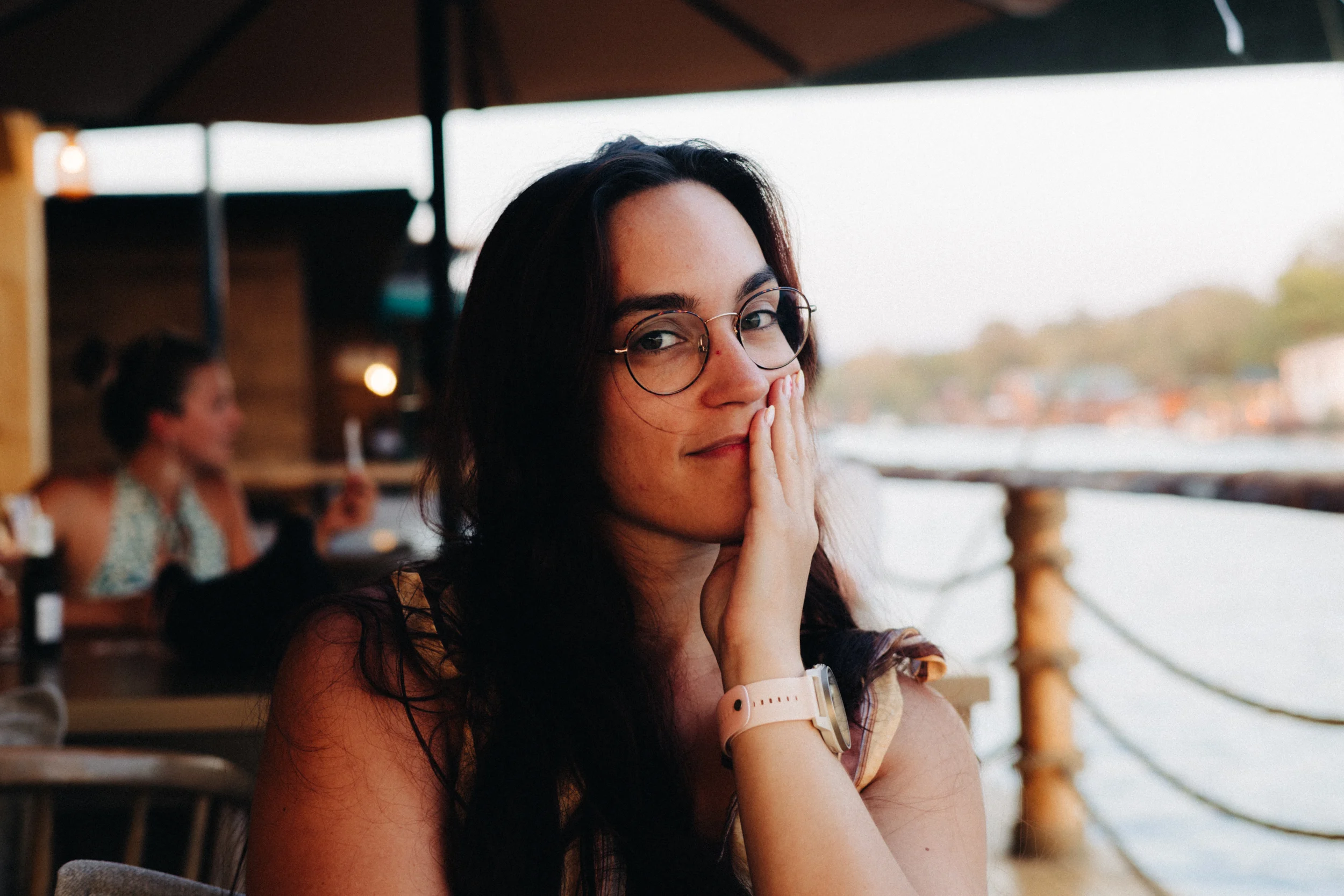 Portrait d'une femme souriante à lunettes à la terrasse d'un restaurant au bord de l'eau