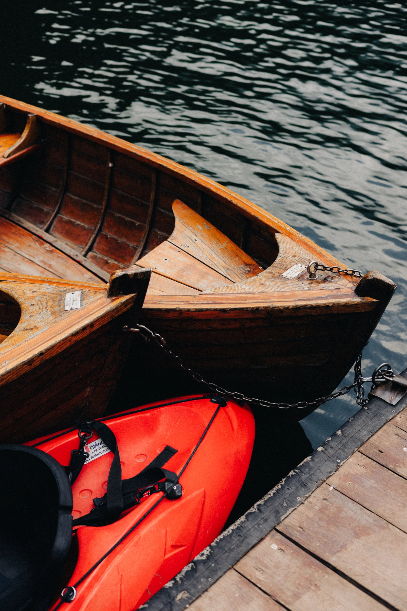 Barques en bois et kayak rouge amarrés à un ponton sur le lac