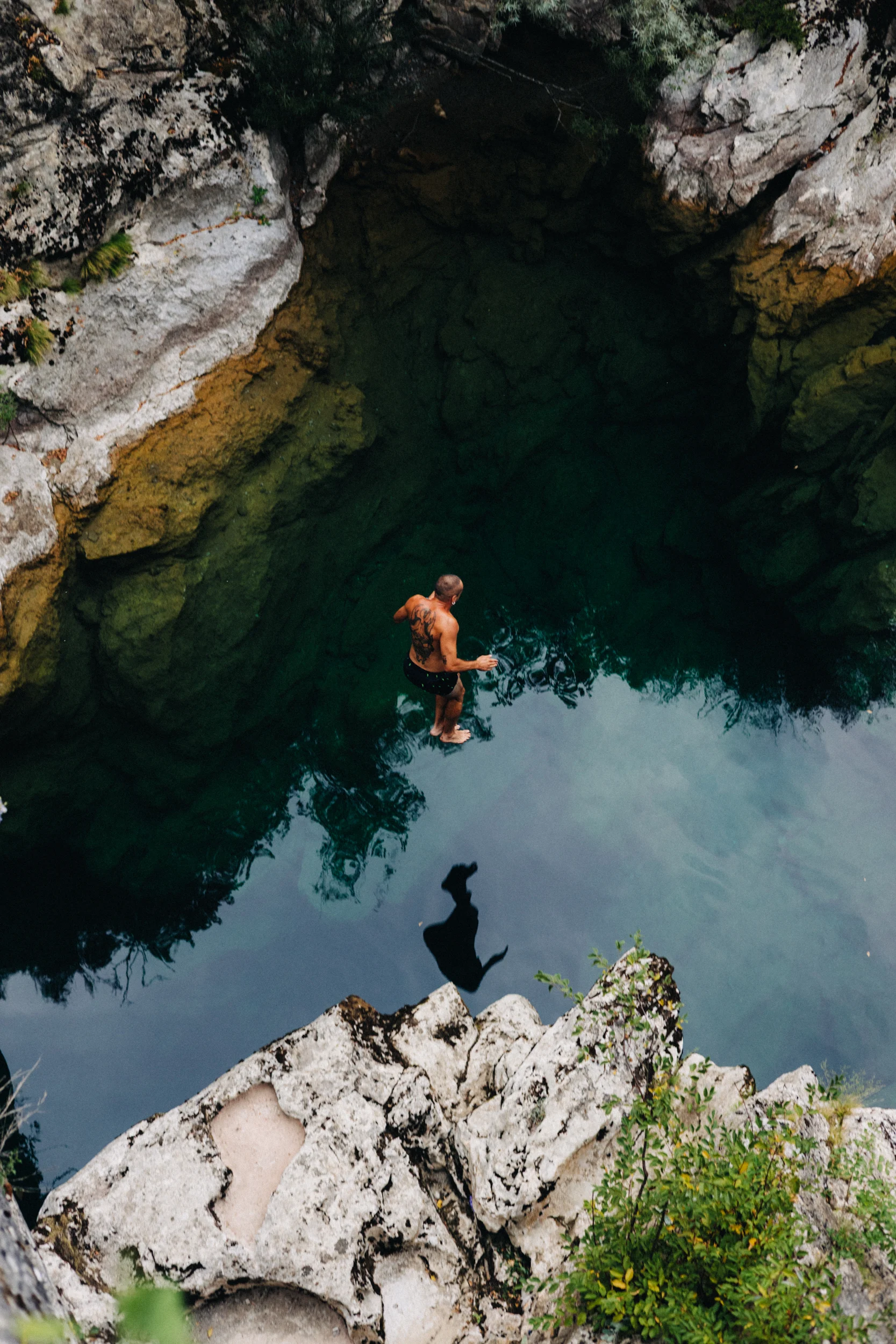 Baigneur dans une vasque d'eau turquoise entre les rochers, vue plongeante